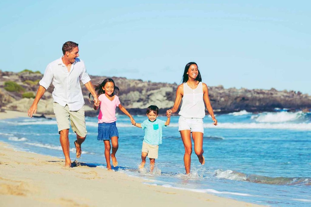 Family walking together along a sandy beach in Hawaii near the ocean